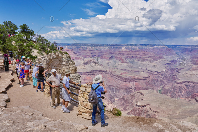 Grand Canyon National Park, Arizona - August 4, 2019: Tourists standing on cliff overlooking canyons