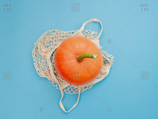 pumpkin in a net bag on blue background