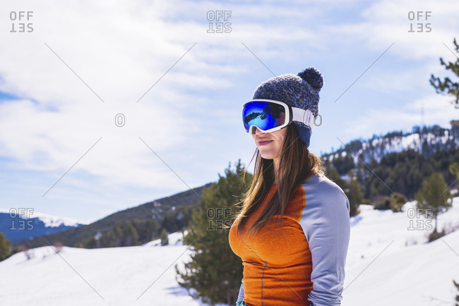 Woman wearing ski clothing standing on snow while looking away to the mountains