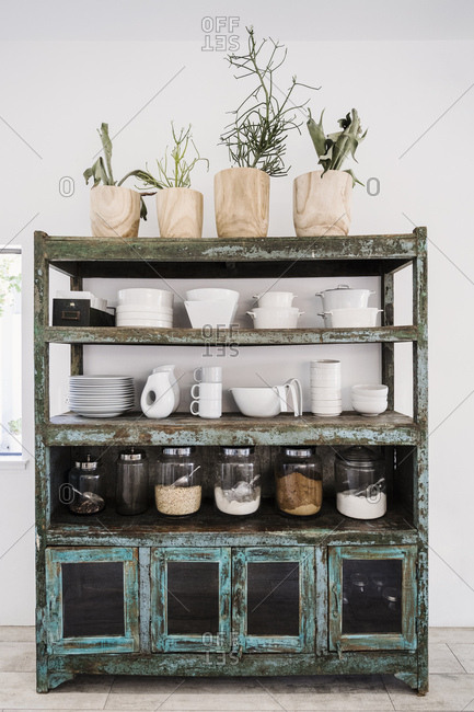 Worn shelves holding tableware, food and potted plants