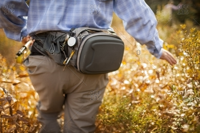 Rear view of man wearing waist pack walking through field