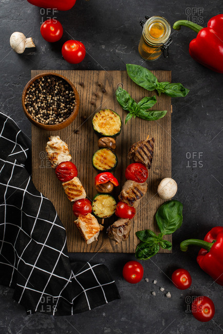 Grilled skewers on cutting board with vegetables