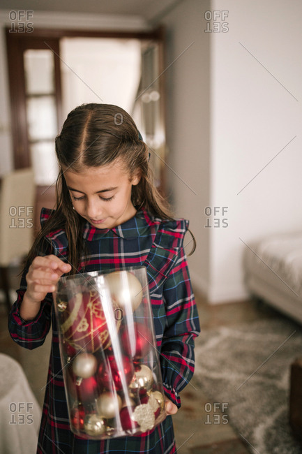 Girl decorating the Christmas tree with red and golden ornaments
