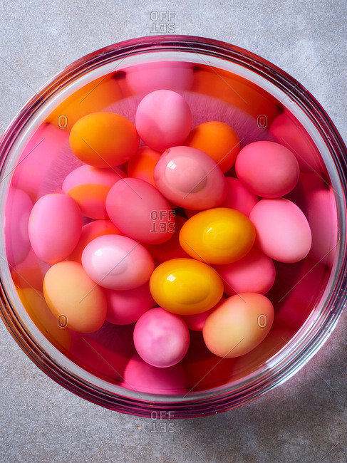 Bowl soaking pastel pink and yellow dyed eggs