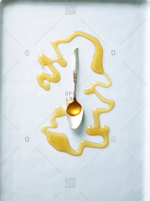 Honey drizzled on white surface with spoon