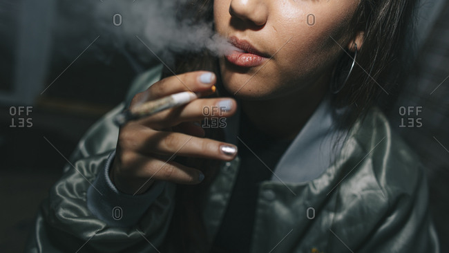Young woman smoking a weed cigarette in urban location