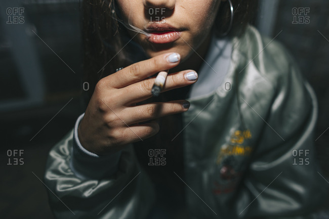 Close up of young woman smoking a weed cigarette in urban location