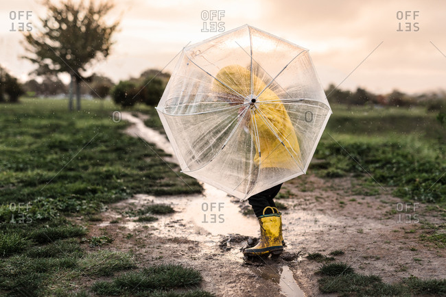 Child playing with umbrella in a mud puddle