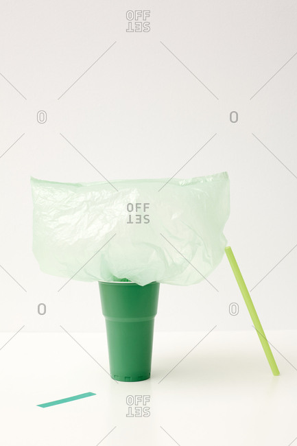 Emerald-green cup, light green straw and plastic bag with piece of tape