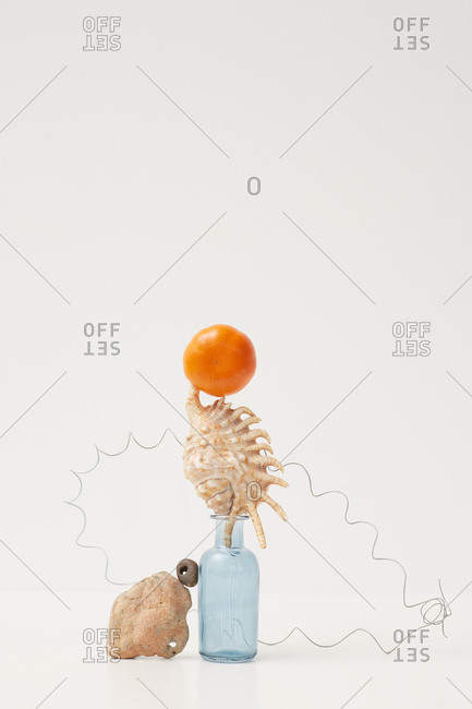 Tangerine, seashell, stones, small glass bottle and wire installation