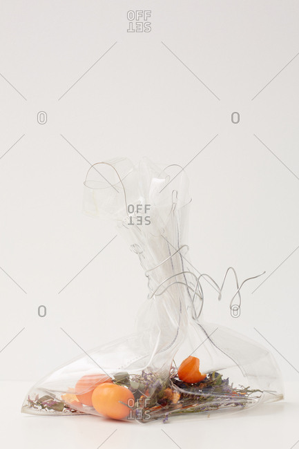 Transparent plastic bag with herbs and tangerines tied with wire