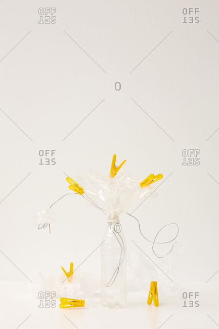 Plastic bottle with bags, wire and yellow clothes pins weird art object