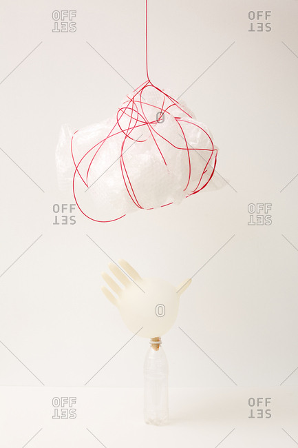 Plastic bag tied with red plastic cord and inflated latex glove on plastic bottle