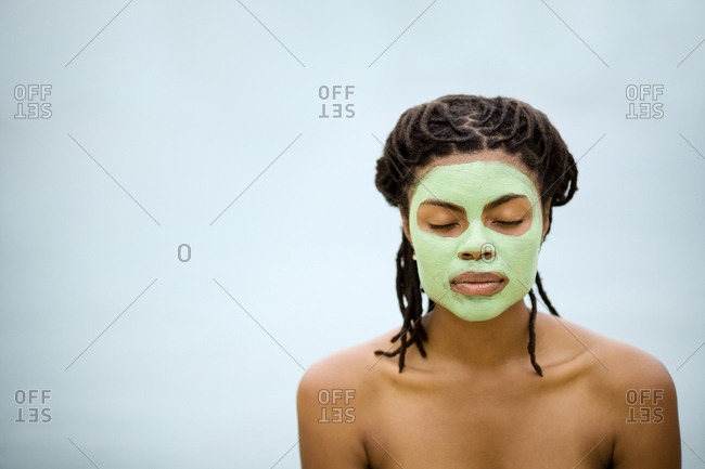 Young woman with a green face mask.