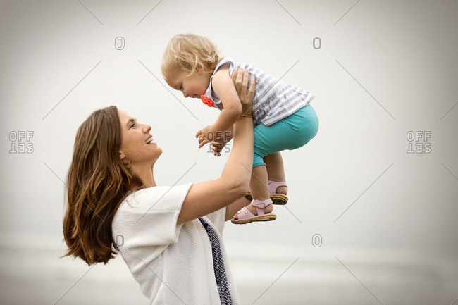 Smiling mother holding her baby daughter in the air.