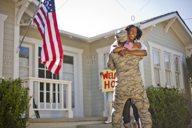 Smiling woman hugging her young son outside their home.