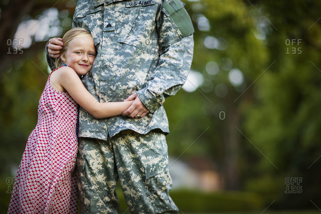 Young girl and mid adult man in army uniform smiling.