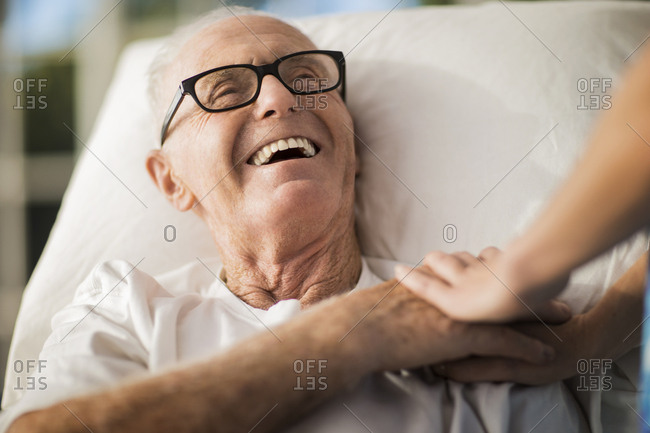 Elderly man in a rest home is cheered up by the gentle touch of a nurse.