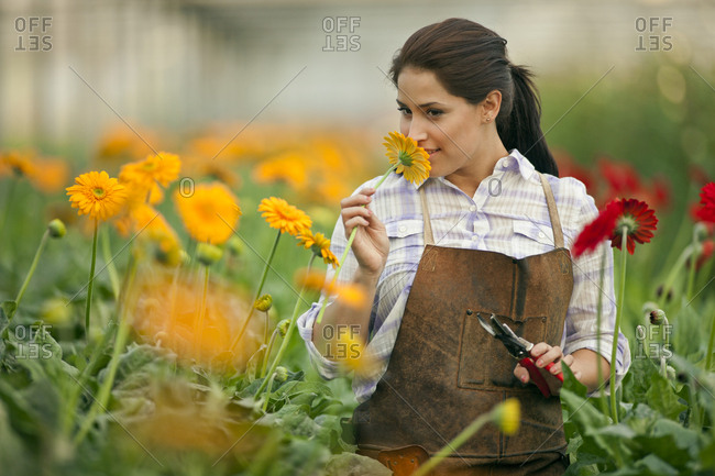 Teenage girl smelling a flower growing in a greenhouse.