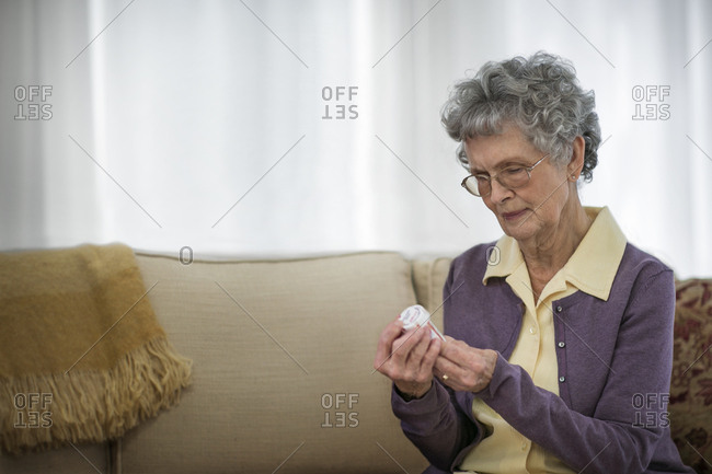 Concerned senior woman reading the label on a bottle of medication.