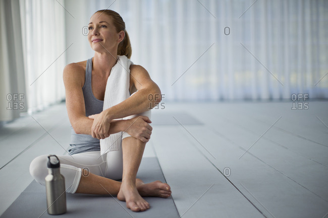 Thoughtful mid adult woman relaxing after a yoga class.