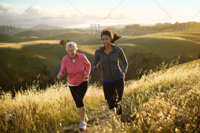 Two women exercising together in a rural landscape.