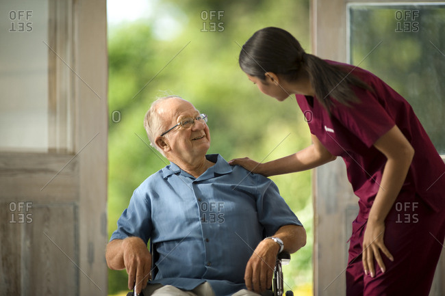 Smiling senior man talking to his young nurse.