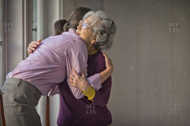 Kind doctor and elderly patient sharing a hug.
