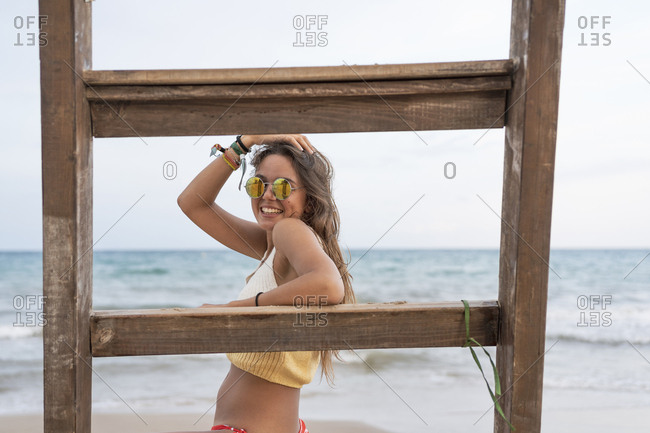 Portrait of happy young woman at a wooden ladder on the beach