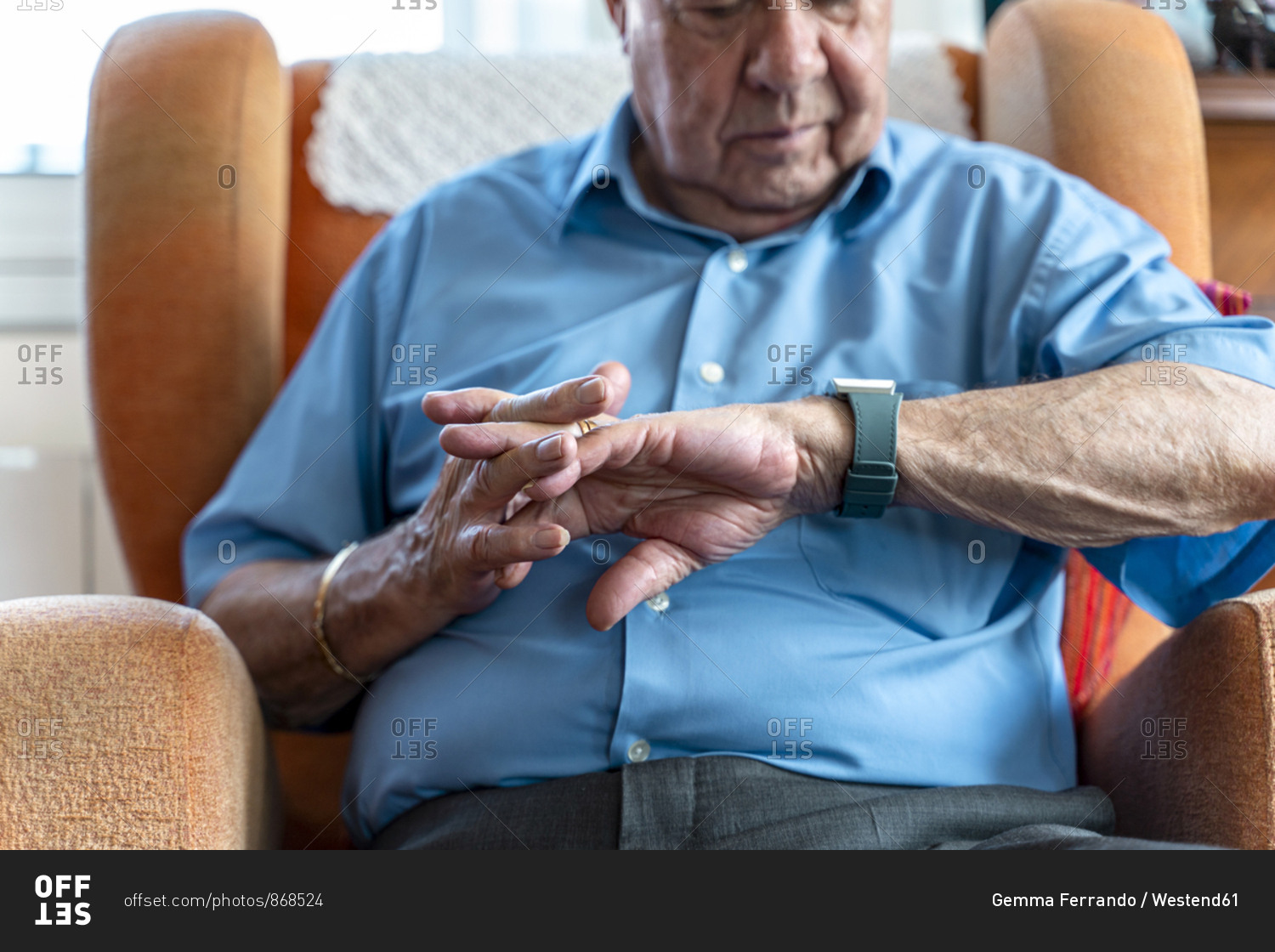 Elderly man wearing a smart emergency alarm bracelet around wrist at home