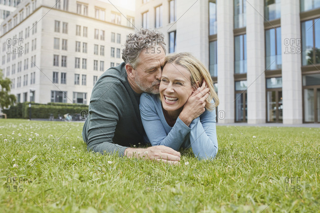 Happy mature couple lying on lawn in the city