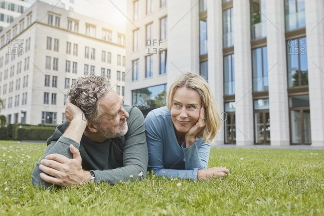Relaxed mature couple lying on lawn in the city