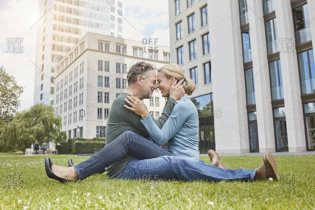 Happy mature couple cuddling on lawn in the city