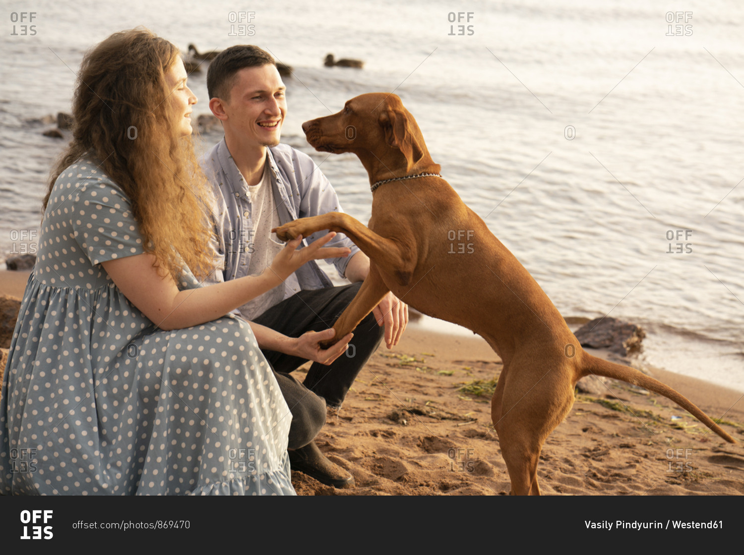 Couple with dog at the beach- dog giving paw