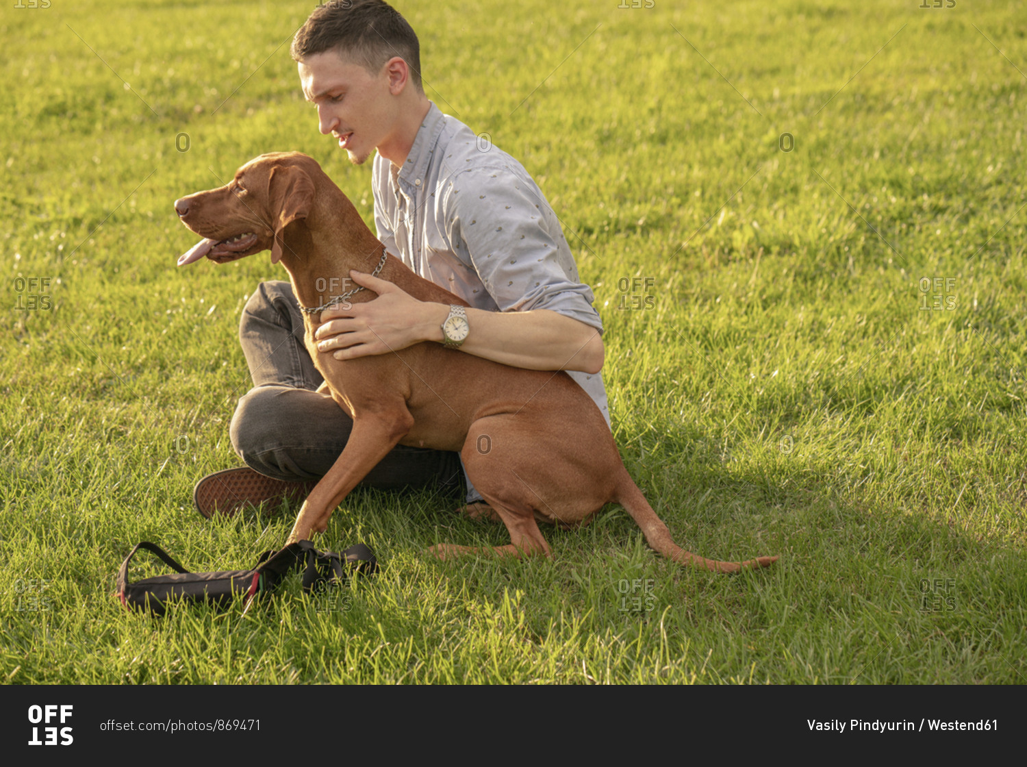 young man with his dog- cuddling on a meadow