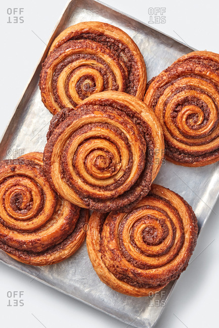 Top view of freshly baked homemade sweet cinnamon buns with spices on a baking sheet on a light grey background, copy space. Top view.