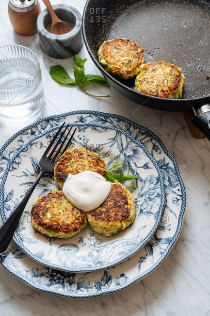 Zucchini fritters in a frying pan and served on a plate
