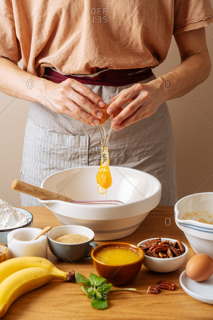 Chef adding an egg into a bowl while preparing a recipe