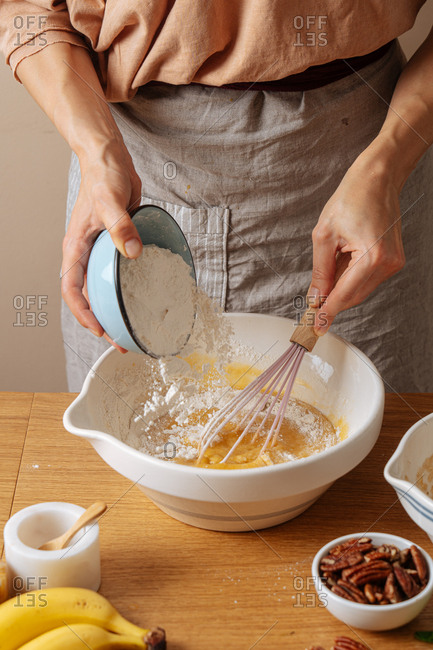 Woman mixing flour into a bowl while preparing a recipe