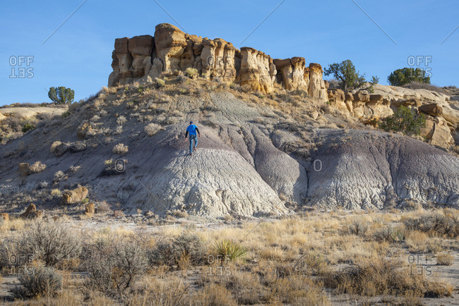 Person hiking among Bisti/De-Na-Zin Wilderness hoodoo sandstone formations, New Mexico
