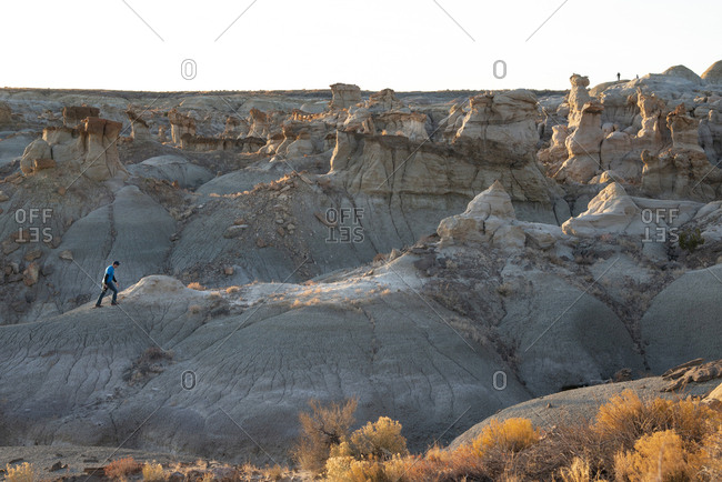 Man hiking on hoodoo sandstone formations in New Mexico's Bisti/De-Na-Zin Wilderness Area