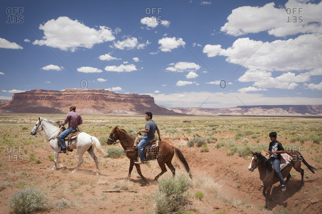 United States, Arizona, Oljato-Monument Valley - June 26, 2010: Horseback riders cross a plain near Monument Valley, Arizona