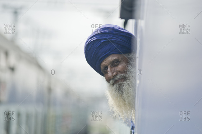 India, Punjab, Amritsar - August 4, 2011: Old Sikh man looks outside a window of the train