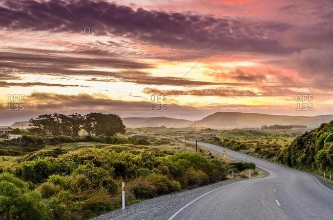 Country road with clouds at sunset, at the Catlins, South Island, New Zealand, Oceania