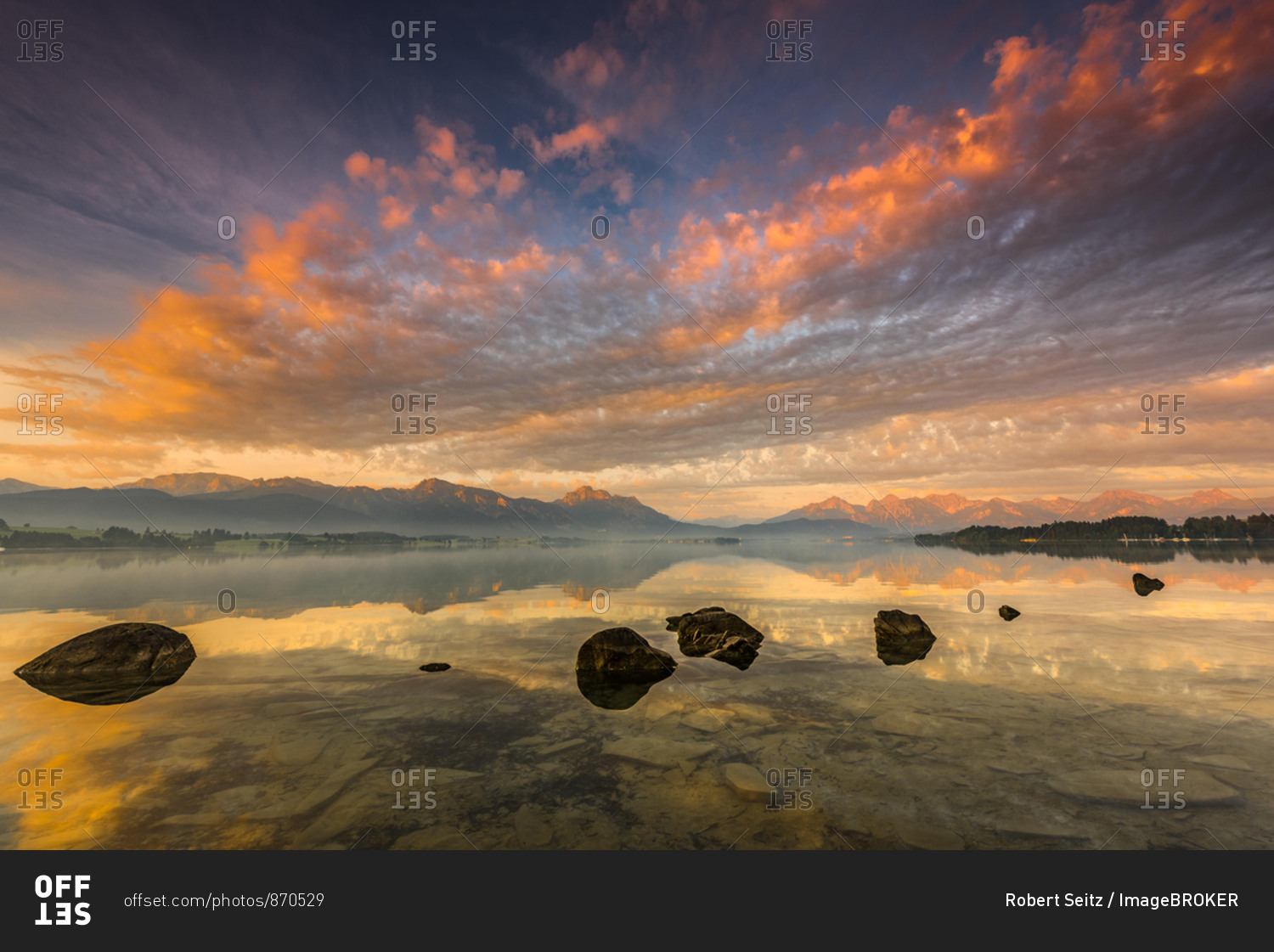 Forggensee with reflection of the cloudy sky and the Allgauer mountains in the background at sunrise, Fussen, Allgau, Bavaria, Germany, Europe