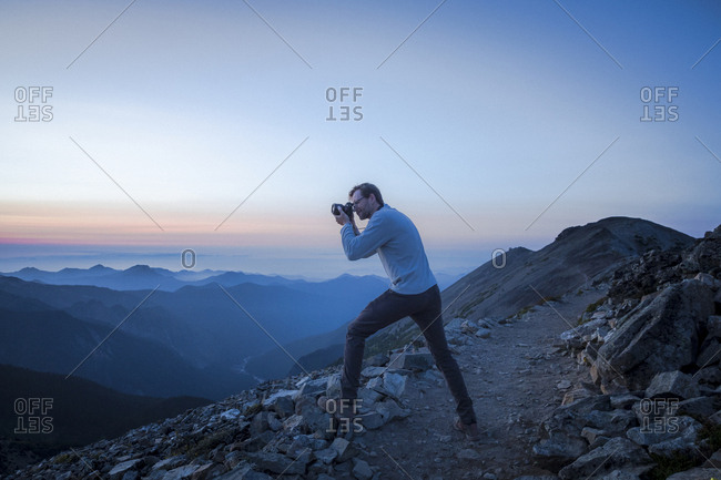 A man is taking pictures of evening mountains in mt. rainier np