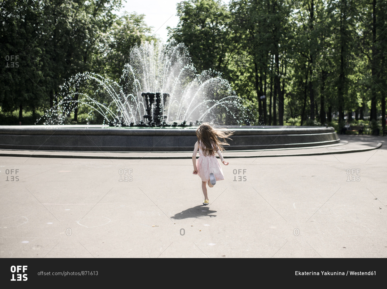 Little girl running towards a fountain