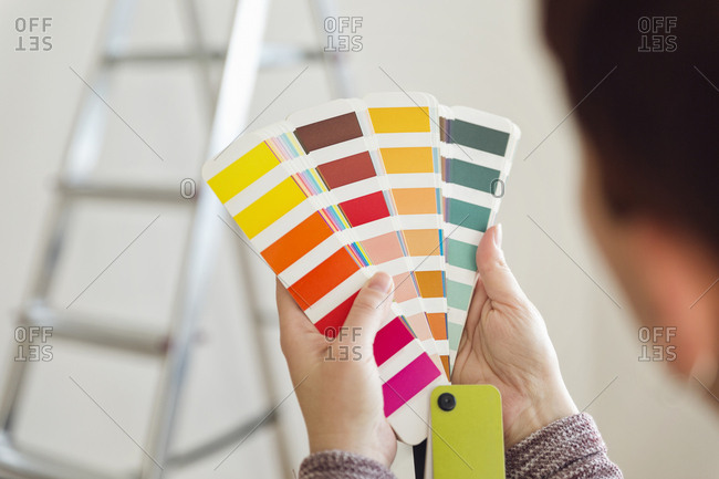 Woman holding color sample in an empty room with a ladder