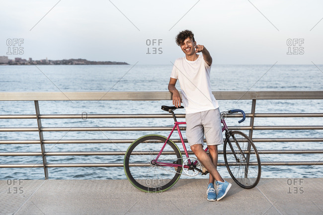 Young man with bicycle-  standing on bridge by the sea