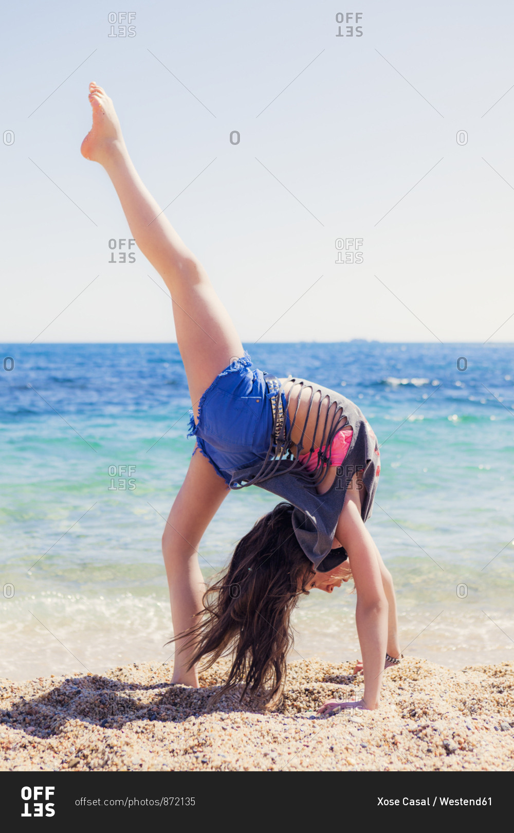Girl doing gymnastics on the beach stock photo OFFSET